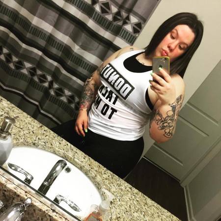 Nicole Covone taking a selfie in a white sleeveless and black pants.